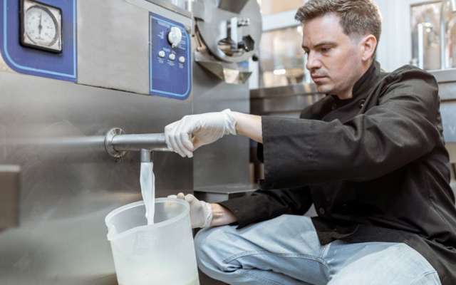Mand som hælder mælk fra pasteurisator